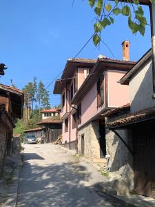 eine leere Straße in einem Dorf mit rosa Häusern in der Unterkunft Карагьозовата Къща in Kopriwschtiza