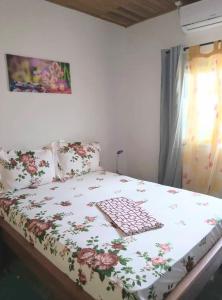 a bed with a floral comforter on it in a bedroom at Résidesnce Merveilles Studio in Kribi
