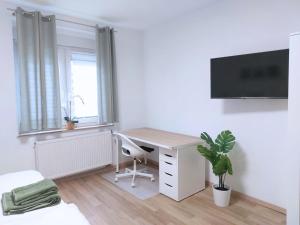 ein Zimmer mit einem Schreibtisch und einem Fernseher an der Wand in der Unterkunft Platz für Gruppen - 4 Schlafzimmer mit TV in Ulm + 5 Fotos