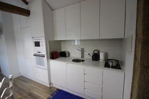 a kitchen with white cabinets and a sink at Casinha Pousafoles in Arouca +4 photos