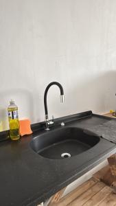 a kitchen sink with a black counter top at Casa Riachuelo in Genuino Sampaio