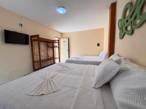 Un dormitorio con dos camas y un televisor de pantalla plana. en Pousada Tabatinga, en Conde