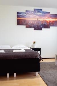 a bedroom with a bed with four paintings on the wall at Railway&bus station studio, parking in Oulu