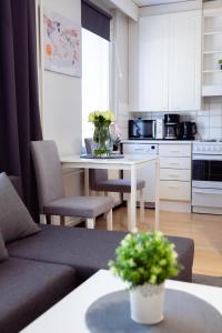 a kitchen with a couch and a table with flowers at Railway&bus station studio, parking in Oulu
