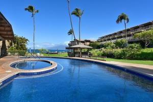 a large swimming pool with palm trees and a building at Kahana Sunset B4B in Lahaina