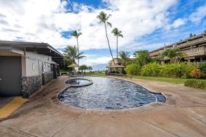 a swimming pool in a courtyard with palm trees at Kahana Sunset B4B in Lahaina