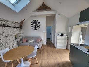 una sala de estar con una mesa y un sofá en Le Gemmois, en Sainte-Gemme-sur-Loire