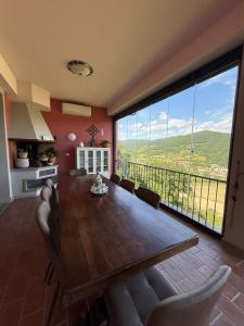 ein Esszimmer mit einem Holztisch und einem großen Fenster in der Unterkunft Charming Guest Room in Villa Casavecchia with City, Garden, and Mountain Views in Dicomano