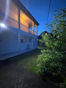 a large white building with a balcony on the side at L'herbe à pic. in Les Abymes