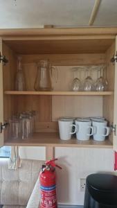 阿伯里斯特威斯Welsh Seaview Stay 3 bed caravan by pool, club and beach的上面有杯子和其他玻璃物品的架子 更多18张照片