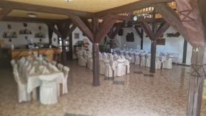 a banquet hall with white tables and chairs in a room at La Neamțu in Văliug