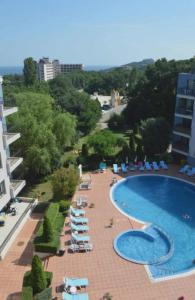 Blick auf ein Schwimmbad, Liegestühle und ein Gebäude in der Unterkunft Апарт комплекс Амфора Палас in Goldstrand