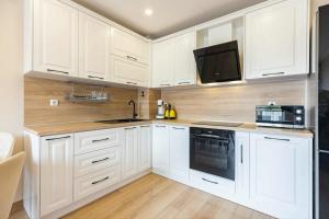 eine Küche mit weißen Schränken und einer Spüle und einer Mikrowelle in der Unterkunft Апарт комплекс Амфора Палас in Goldstrand