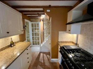 eine Küche mit weißen Schränken und einem Herd mit Backofen in der Unterkunft The Carriage House in Blockley + 15 Fotos