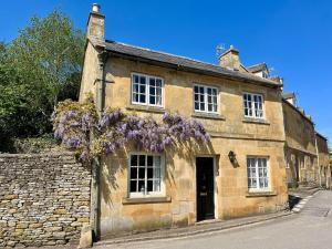 an old stone building with purple flowers on it at The Carriage House in Blockley