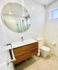 a bathroom with a sink and a mirror and a toilet at Prickly Pear Stays in Merewether - Ranclaud St in Merewether