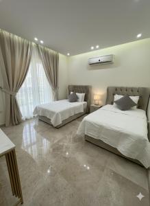 a bedroom with two beds and a large window at 3BR 5Bed luxury apartment in Jeddah