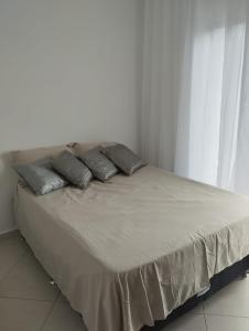 a bed with three pillows on it in a room at Sobrado Harmonia in Ponta Grossa