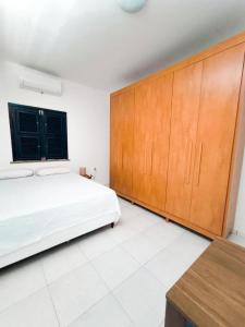 ein Schlafzimmer mit einem Bett und Holzschränken in der Unterkunft Casa Mahalo - no centro de Cumbuco in Caucaia