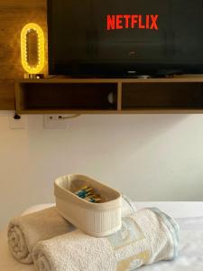 un bol de brosses à dents posé sur une serviette devant la télévision dans l'établissement Studio Charmoso 2km do Aeroporto de Congonhas, à São Paulo