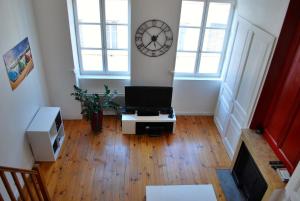 sala de estar con TV y reloj en la pared en L'Appartement du Parc, en Lyon