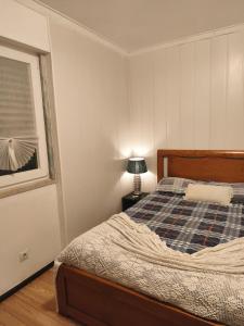 a bedroom with a bed and a lamp and a window at Ginjals-67 Quarto Branco in Almargem do Bispo