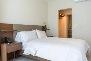 Un dormitorio con una cama blanca y un teléfono. en 2-BR with Urban Skyline Views in Panama City, en Panamá