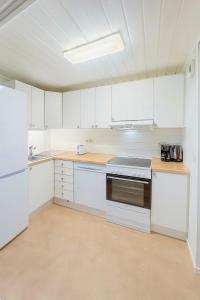 an empty kitchen with white cabinets and a stove at Sentralt og elegant opphold nær alt in Lillehammer