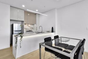 悉尼Stunning Wyndel Macquarie Apartment的厨房配有玻璃桌和黑色椅子