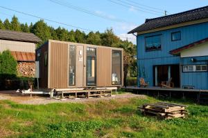 a building with a modular home next to a house at Kirisawabase Tiny House by Tiny Away in Nagaoka