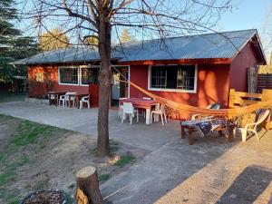 a red house with a hammock in front of it at Playa Hostel in Santa Rosa de Calamuchita