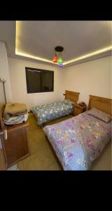 a bedroom with two beds and a flat screen tv at Residence Ritaj in Agadir