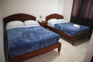 ラス・タブラスにあるvilla Tableñaの小さな部屋に青いシーツが敷かれたベッドが2つ