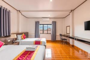 a hotel room with two beds and a desk at VangVieng Charming Boutique Hotel in Vang Vieng