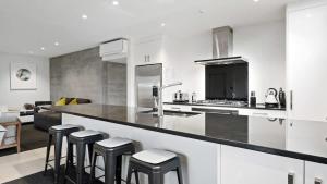 a kitchen with a counter and stools in a room at Diamond Luxury Central Queenstown in Queenstown