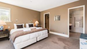 a bedroom with a large white bed and a mirror at Stewart Lodge Luxury Spa in Queenstown