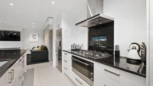 a large white kitchen with a stove top oven at Diamond Luxury Central Queenstown in Queenstown +16 photos