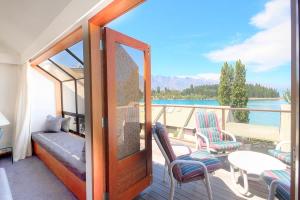 a room with a balcony with a view of the water at The Lodges in Queenstown
