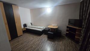 a room with a chair and a table and a television at Flamingo Hotel in Bistriţa