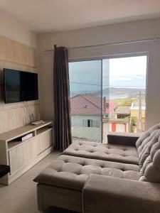 un soggiorno con un grande divano e una grande finestra di Casa com vista para o mar e perto do centro a Imbituba