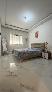 a bedroom with a bed in a white room at Dolce Vita Appartement in El Aouina Station