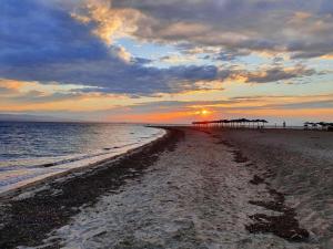 a sunset on the beach with a pier in the distance at Oasis room in Néa Michanióna +1 photo