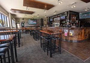 a bar with tables and stools in a restaurant at Recreation Hotel in Greymouth