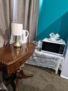 une table avec un micro-ondes sur une table avec une lampe dans l'établissement Master bedroom, à Tauranga