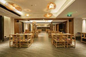 a restaurant with tables and chairs in a room at 品缦芸酒店长沙高铁南站沙湾公园地铁站店 in Changsha