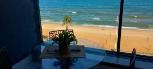 萨尔瓦多Studio Luxuoso vista Mar的沙滩上放着一张玻璃桌，桌上摆着一盆植物。