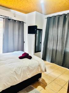 ein Schlafzimmer mit einem großen Bett mit grauen Vorhängen in der Unterkunft BTV Holiday Home in Hazyview