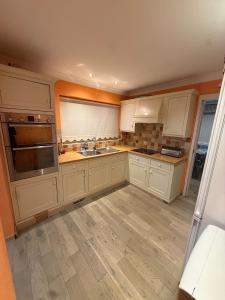 une cuisine vide avec des placards blancs et un évier dans l'établissement A lovely bungalow with 3 bedrooms and nice garden, à Boultham