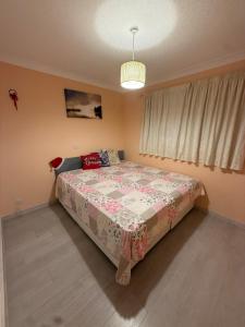 une chambre avec un grand lit avec une couverture fleurie dans l'établissement A lovely bungalow with 3 bedrooms and nice garden, à Boultham