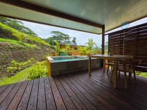 una terraza con bañera de hidromasaje, mesa y sillas en Revatua Lodge - Piscine privée et Petit-déjeuner inclus,  4 fotos más